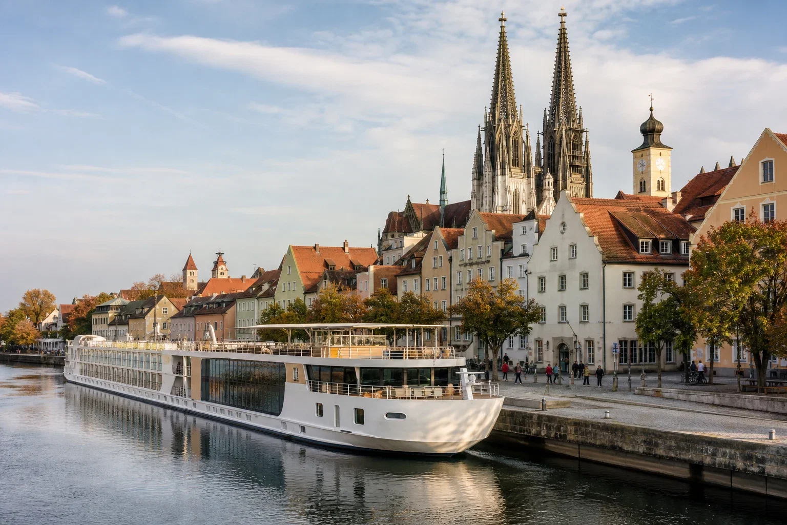Small river cruise ship moored at a picturesque European town center with a cathedral spire in the background